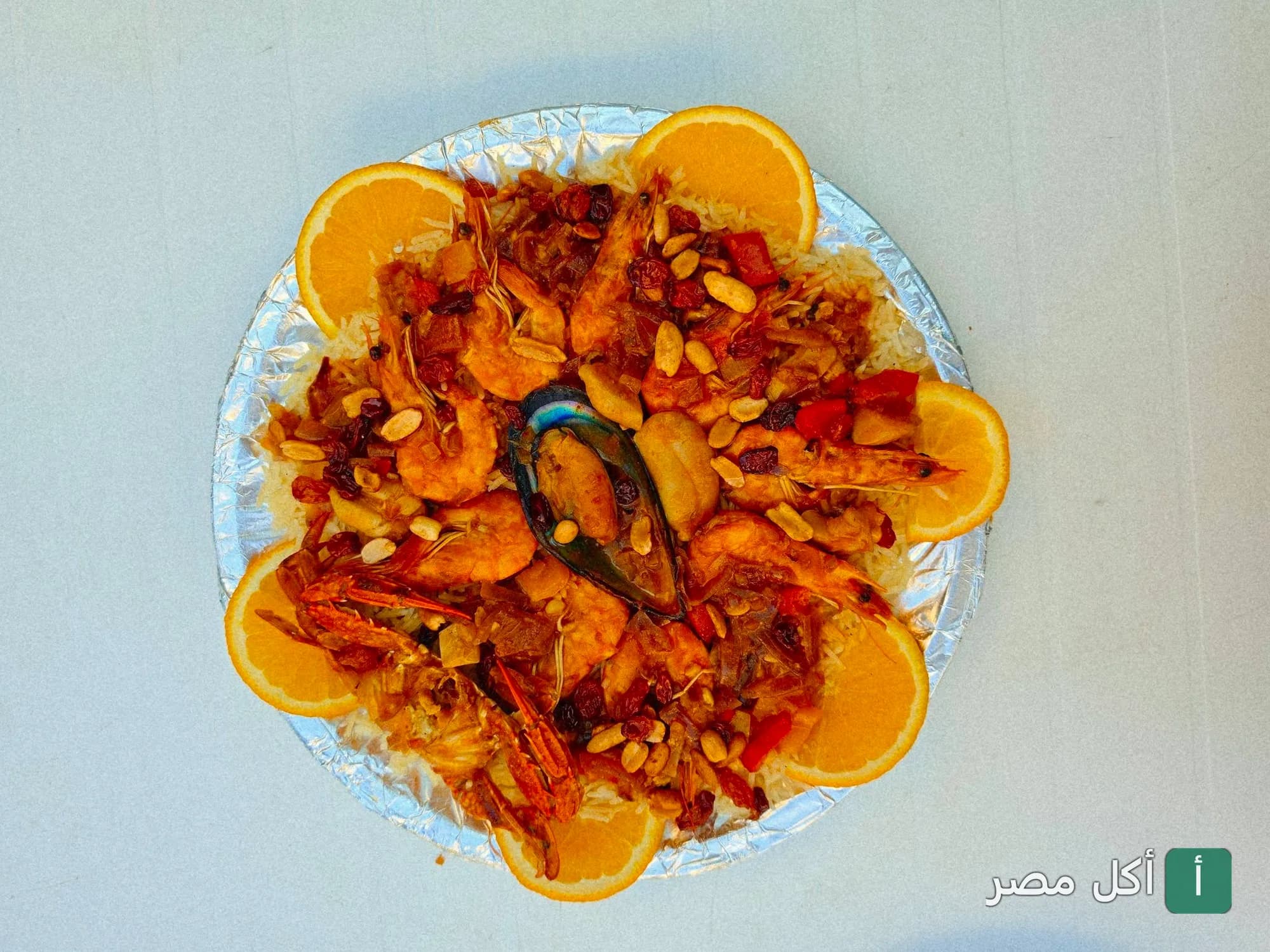 طبق أرز بالمأكولات البحرية والجمبري مزين بشرائح البرتقال في مطعم أسماك الزفر بالعامرية