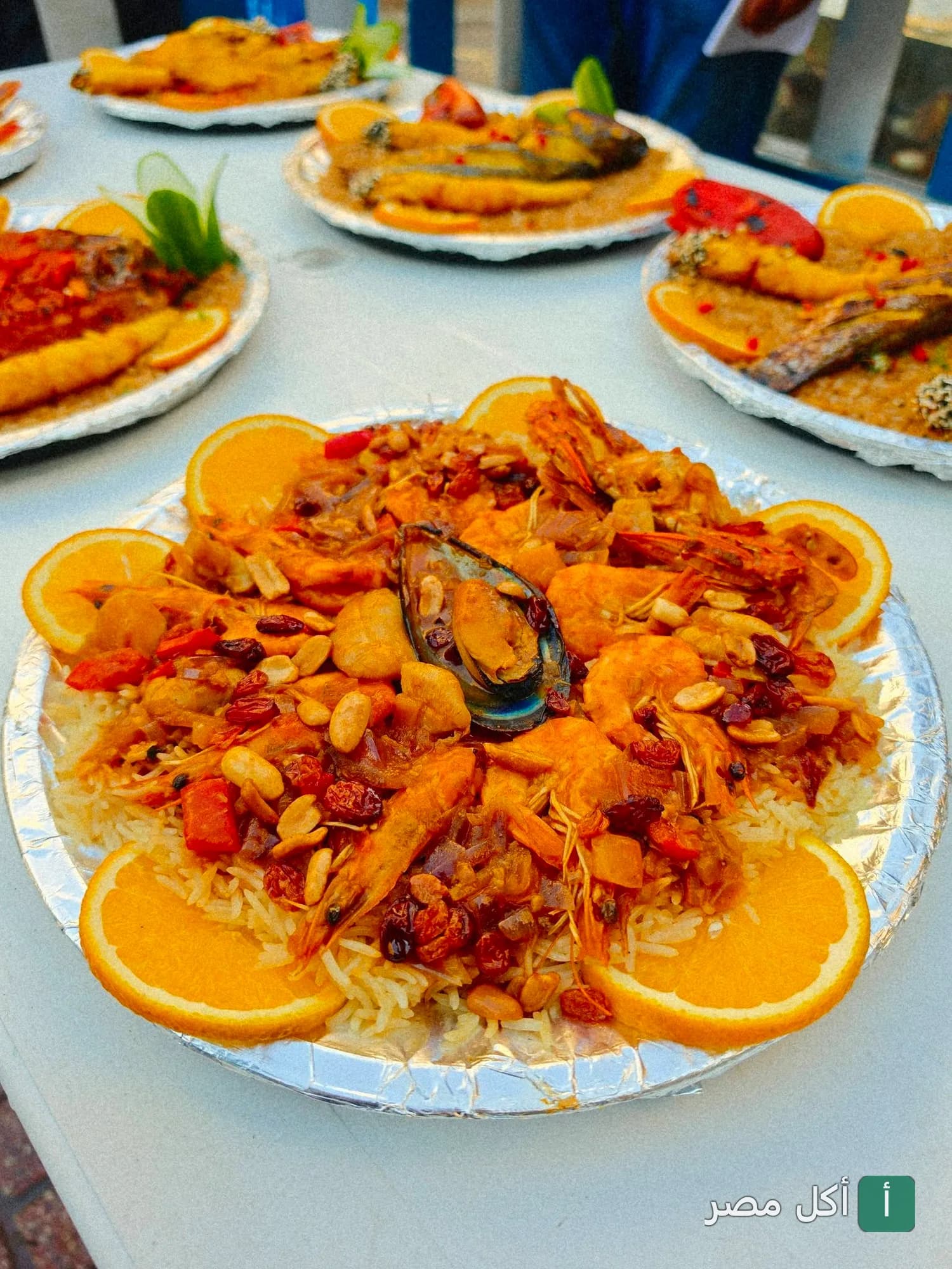 أطباق أرز بالمأكولات البحرية والجمبري مزينة بشرائح البرتقال في مطعم أسماك الزفر بالعامرية.