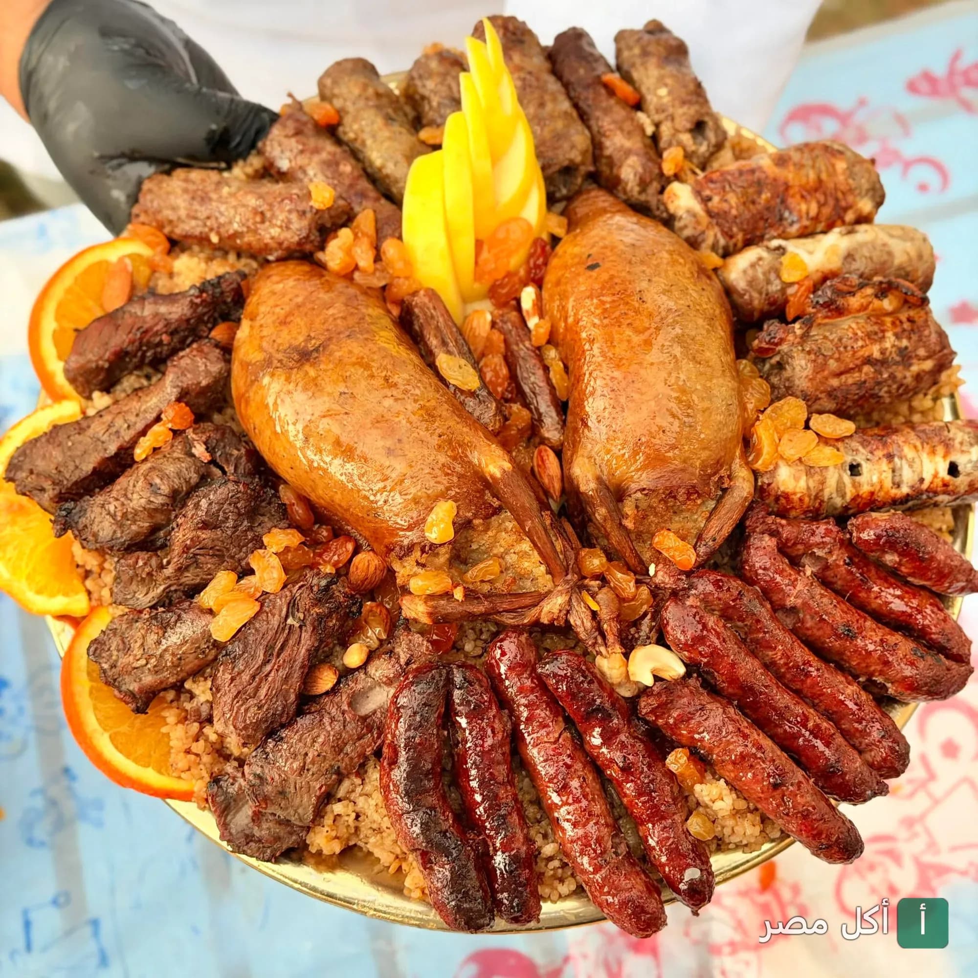 طبق مشاوي مشكل من مطعم طعم زمان في بور فؤاد، يحتوي على حمام محشي وكفتة وسجق مع أرز ومزين بشرائح البرتقال.
