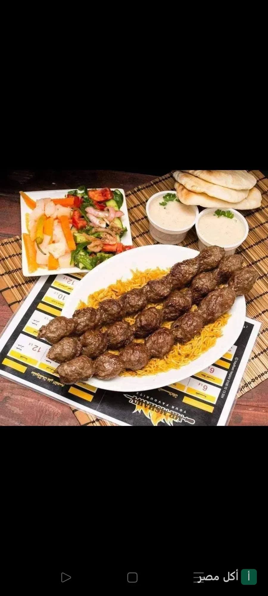 طبق كفتة مشوية على أرز أصفر مع سلطة خضراء وطحينة وخبز في مطعم مستر مشاوي ببور فؤاد.
