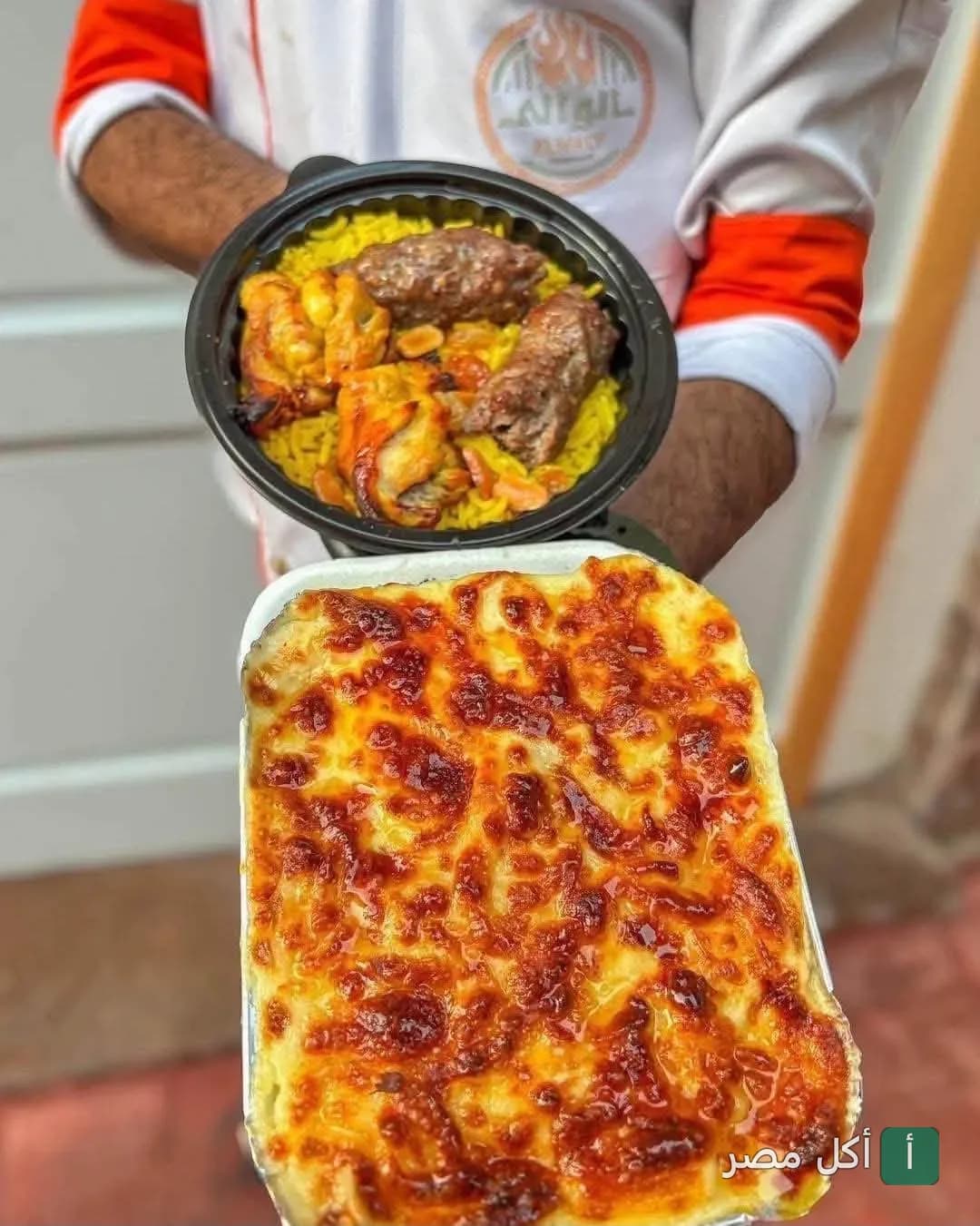 موظف مطعم الوالي ببور فؤاد يحمل وجبة أرز بالمشويات وطبق مكرونة بالبشاميل.