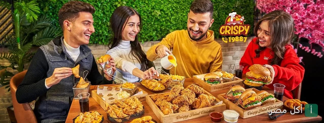 مجموعة أصدقاء يتناولون وجبات الدجاج المقلي والبرجر في مطعم كرسبى فرايد تشيكن بالزهور في بورسعيد.