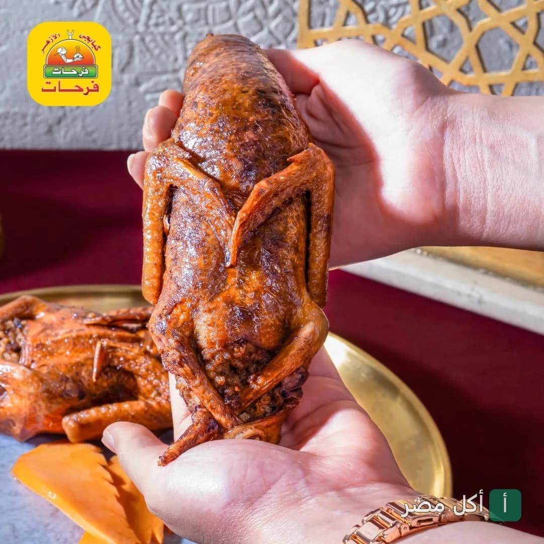 شخص يمسك حمام محشي محمر من مطعم كبابجي الأزهر فرحات في الجمالية.