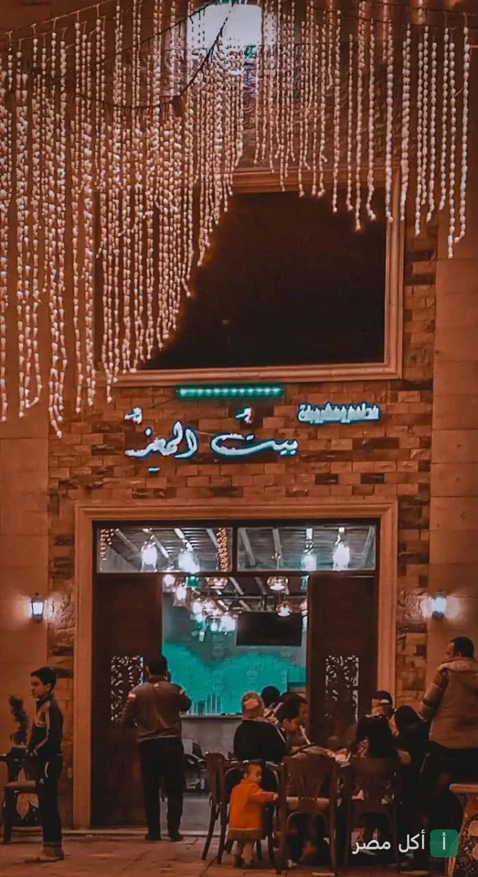 واجهة مطعم وكافيه بيت المعز في الجمالية مع إضاءة ليلية وديكورات خشبية.