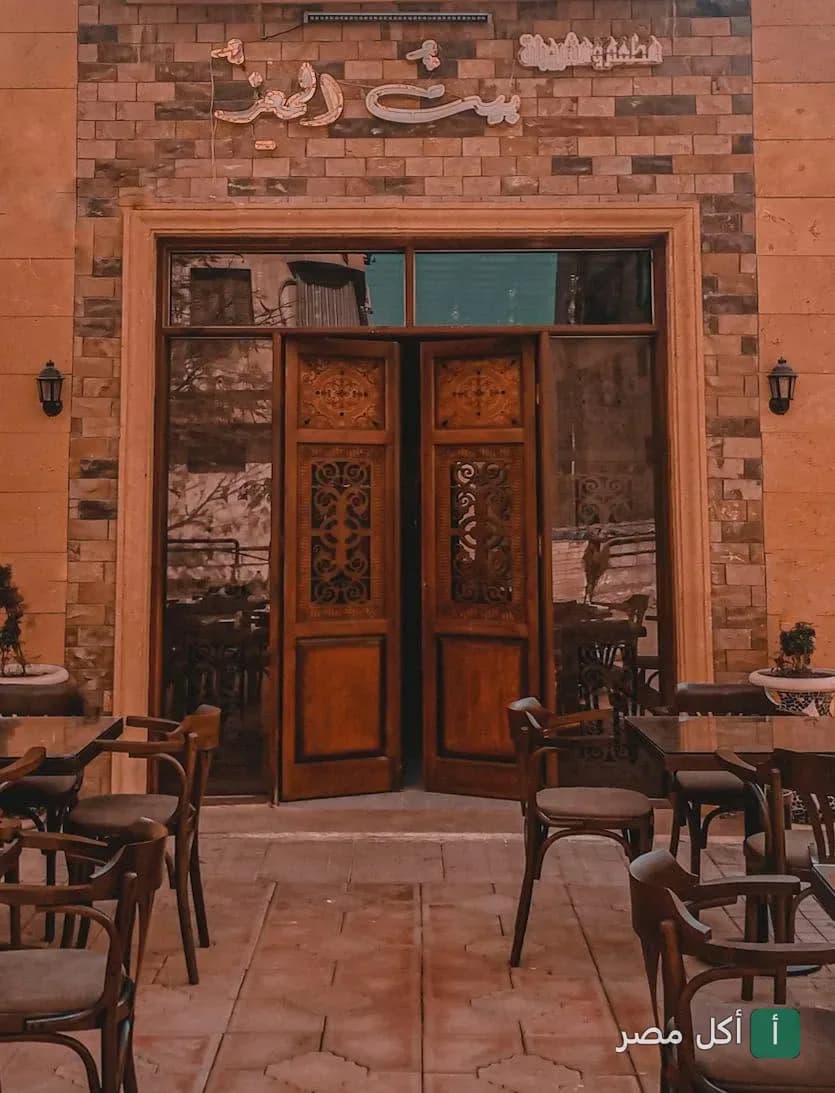 واجهة مطعم وكافيه بيت المعز في الجمالية مع جلسات خارجية خشبية وأبواب ذات طراز تراثي.