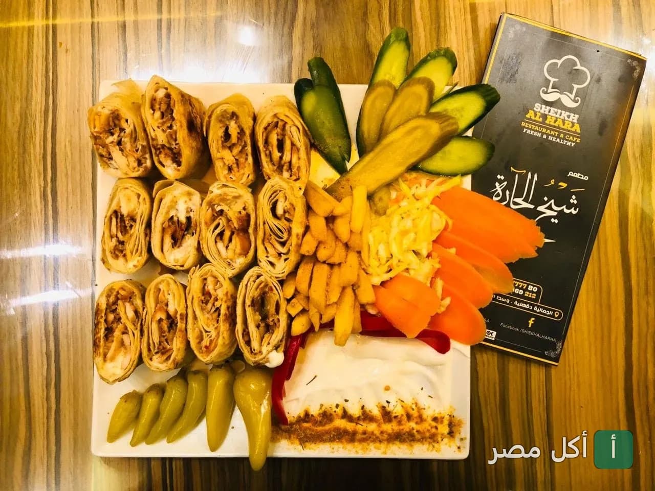 طبق شاورما مقطع مع بطاطس ومخللات بجانب قائمة طعام مطعم شيخ الحارة في الجمالية.