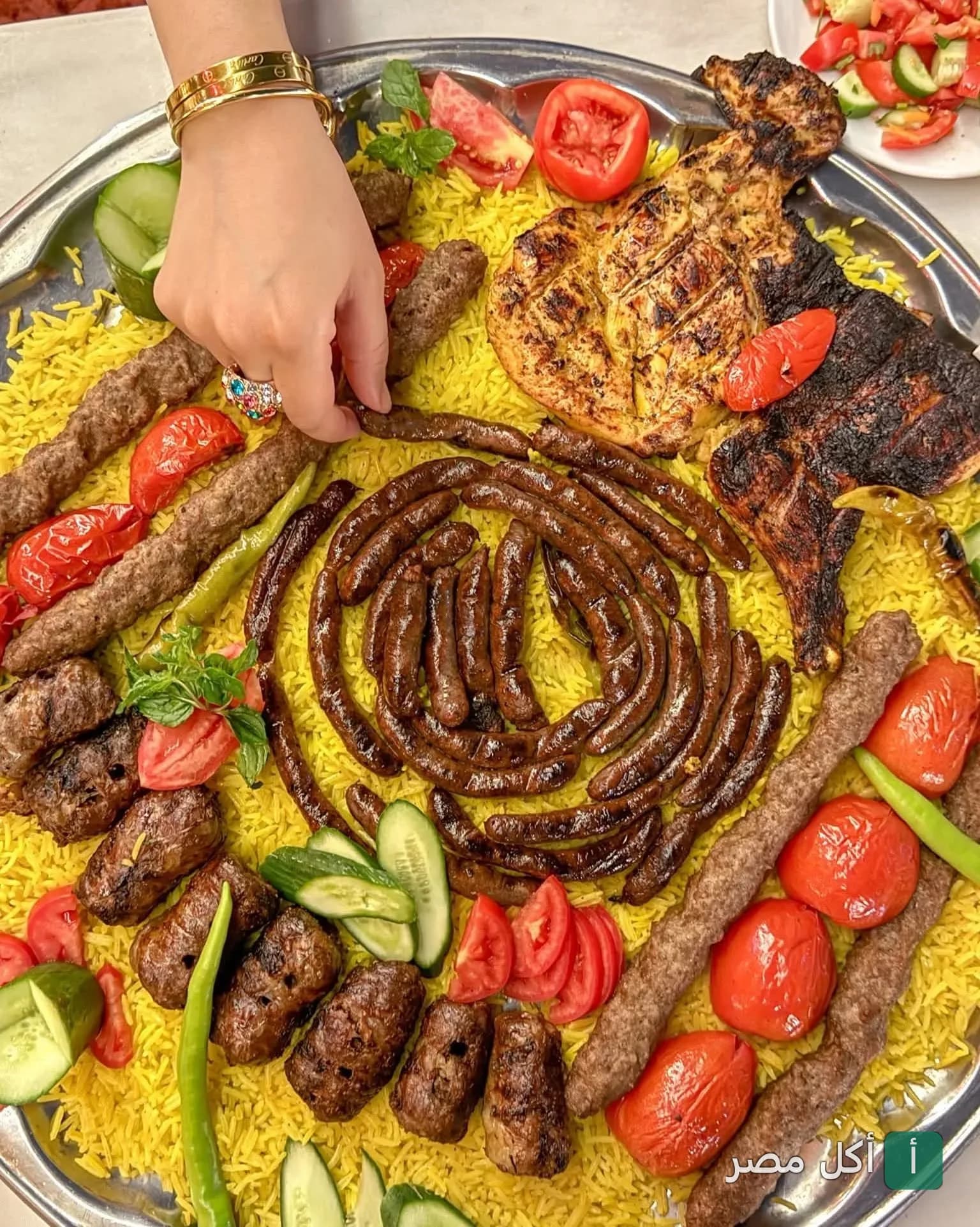 صينية مشويات متنوعة من مطعم بابا عبده بباب الفتوح، تضم كفتة وسجق ودجاج مشوي مع أرز أصفر وخضروات.