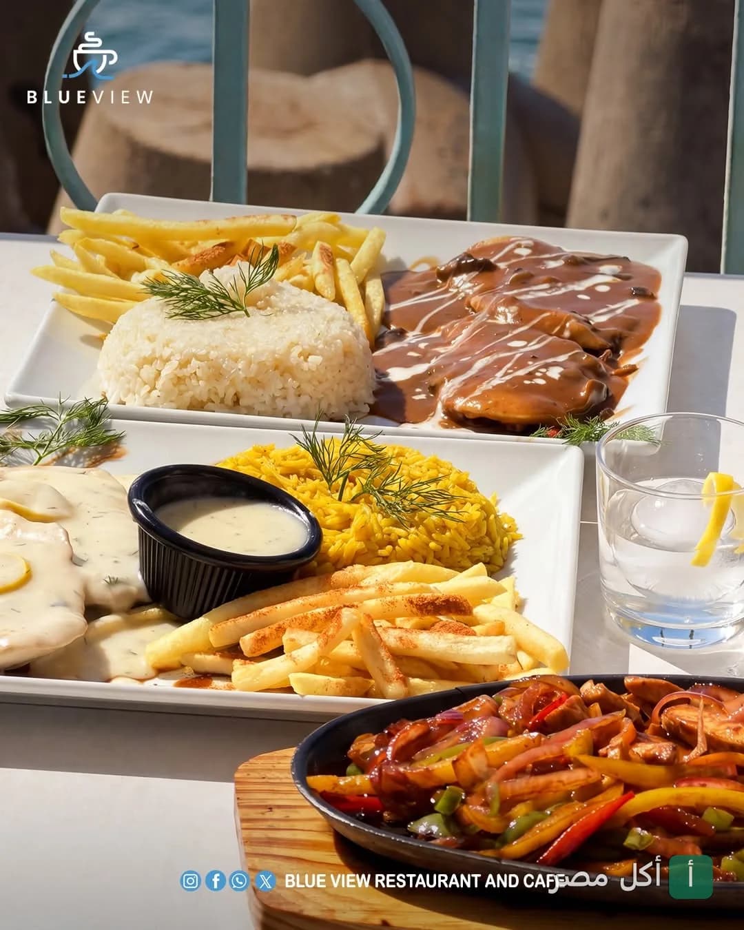 أطباق متنوعة من مطعم بلو فيو في سيدي جابر، تشمل أطباق رئيسية مع أرز وبطاطس مقلية ووجبة فاهيتا على طاولة خارجية.