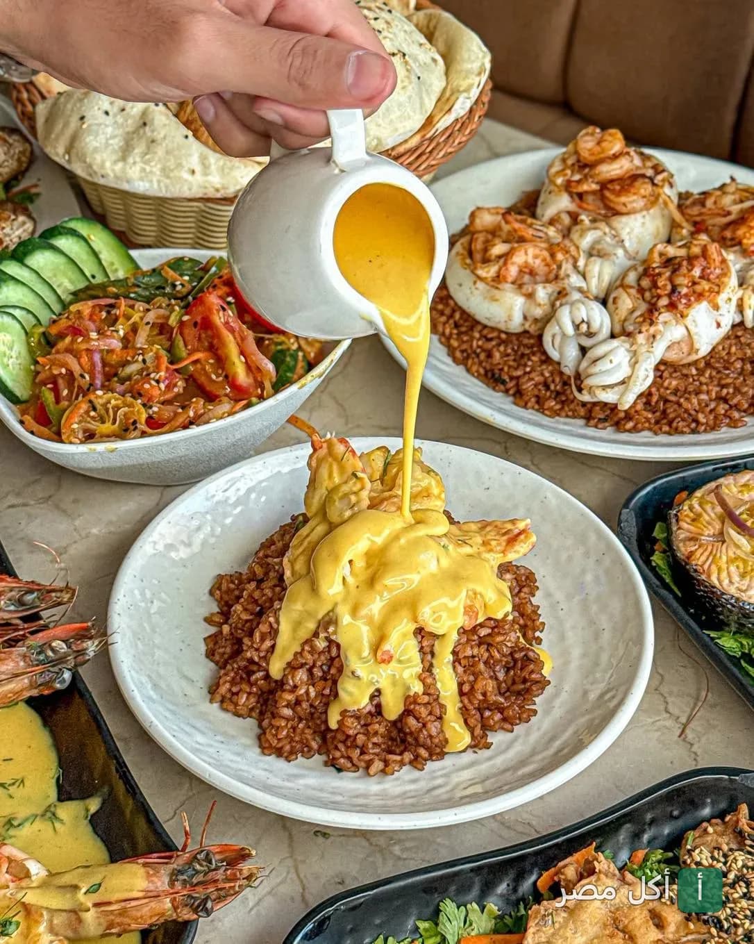 صب صوص أصفر على طبق أرز بالجمبري في مطعم لقمه بحر بسيدي جابر بالإسكندرية.