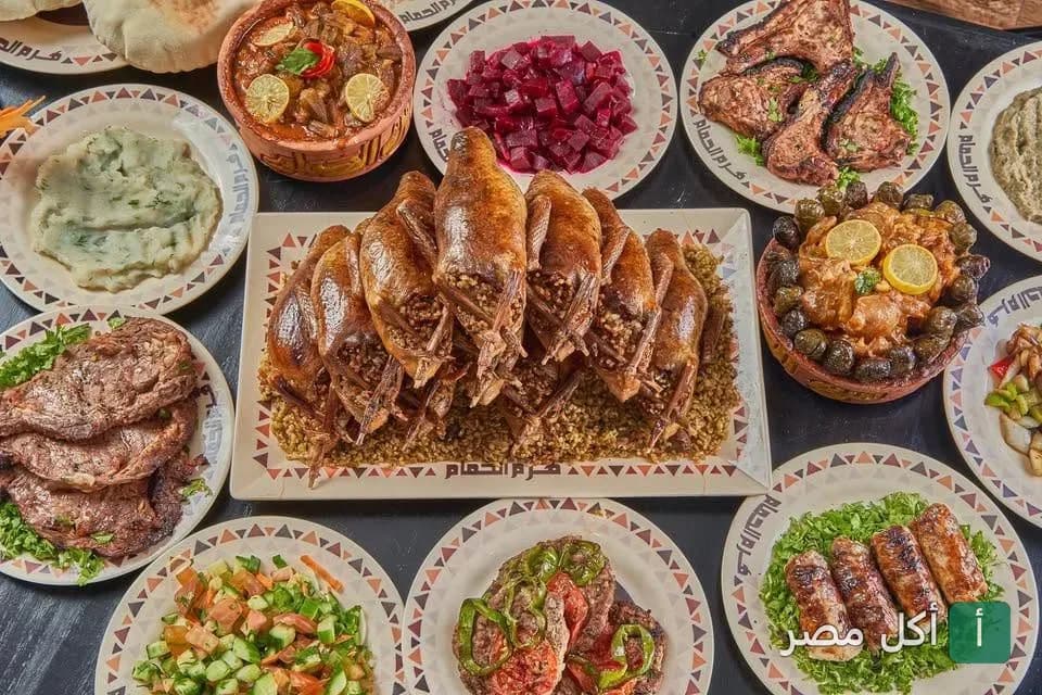سفرة مليانة أطباق مشويات متنوعة وحمام محشي من مطعم هرم الحمام في سيدي جابر بالإسكندرية.