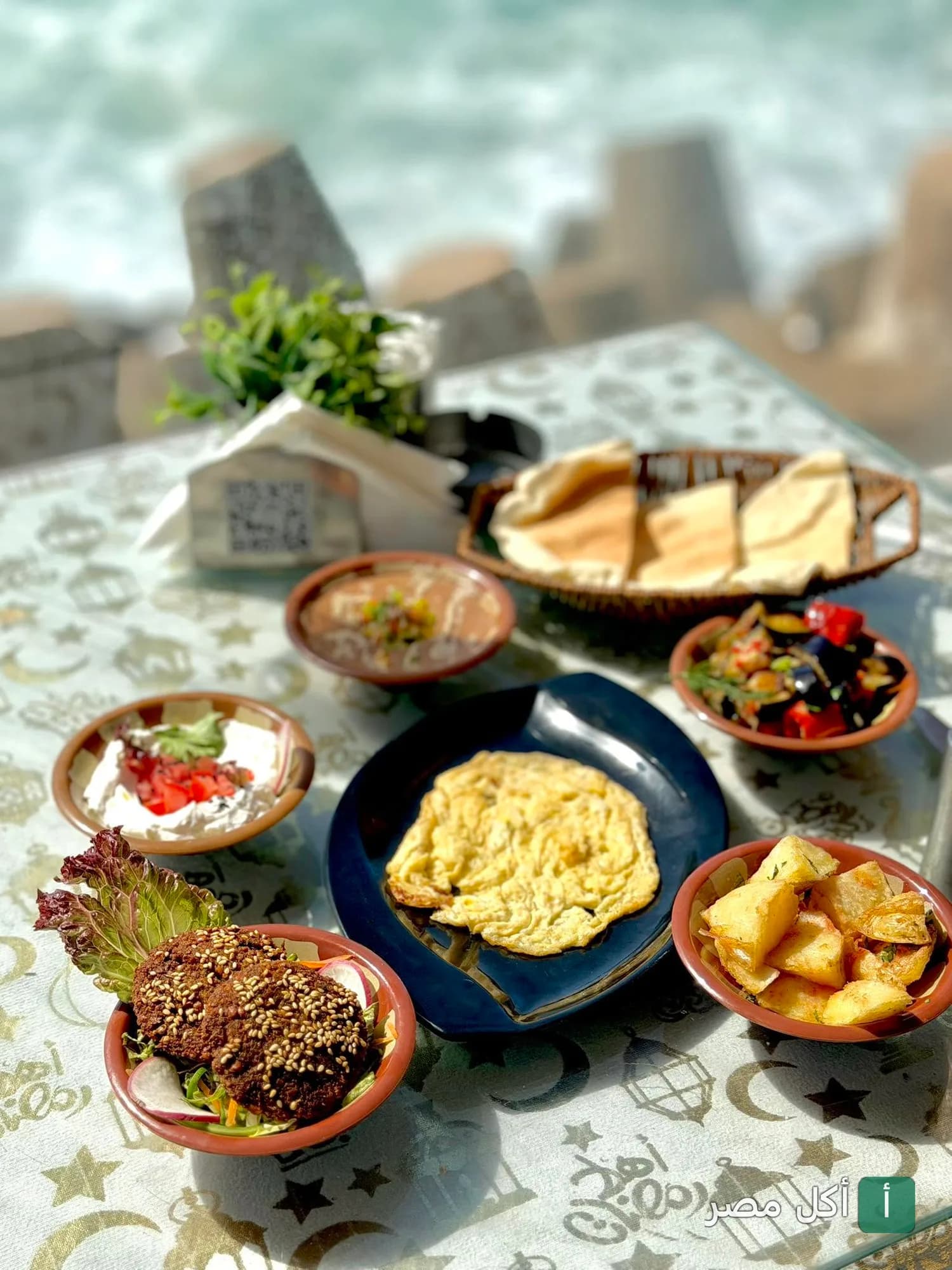 مائدة إفطار متنوعة تضم طعمية وبيض وبطاطس ومقبلات في مطعم وودز بسيدي جابر أمام البحر.