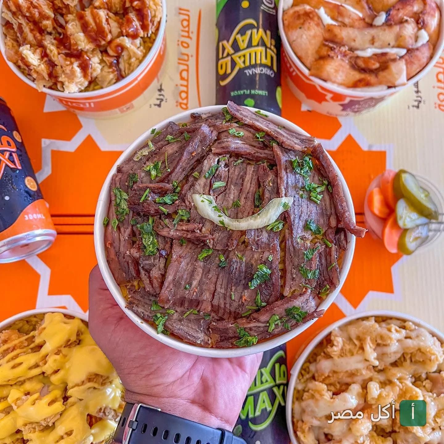 يد تحمل طبق شاورما لحم مع أرز ومخلل من مطعم خواطر دمشقية في سيدي جابر بالإسكندرية.