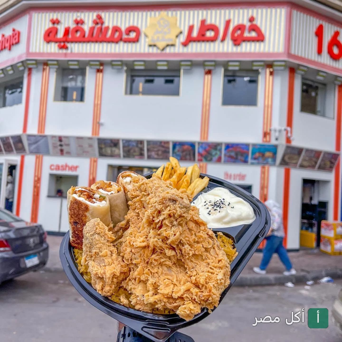 وجبة دجاج مقلي مع شاورما وبطاطس أمام واجهة مطعم خواطر دمشقية في سيدي جابر بالإسكندرية.