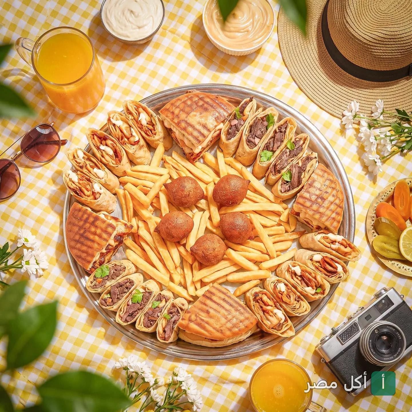 صينية وجبات سريعة متنوعة من مطعم خواطر دمشقية في سيدي جابر، تضم سندوتشات شاورما، كبة، وبطاطس مقلية.