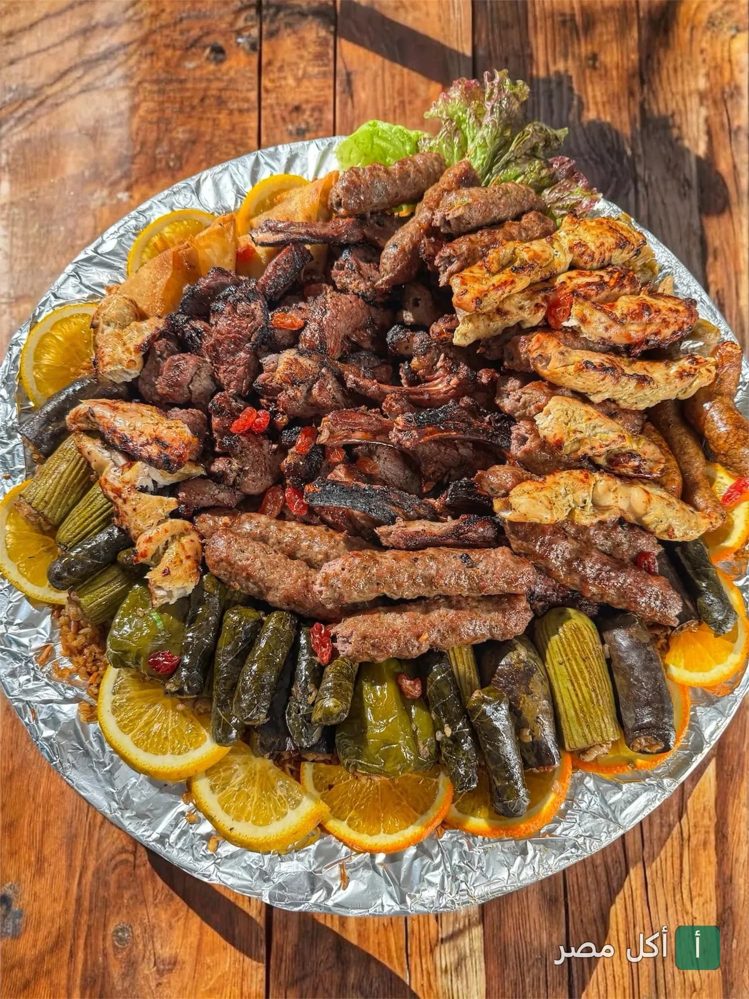 طبق مشويات مشكل من مطعم الوطنية في طنطا يضم كفتة وشيش طاووق ومحاشي مزين بشرائح البرتقال.