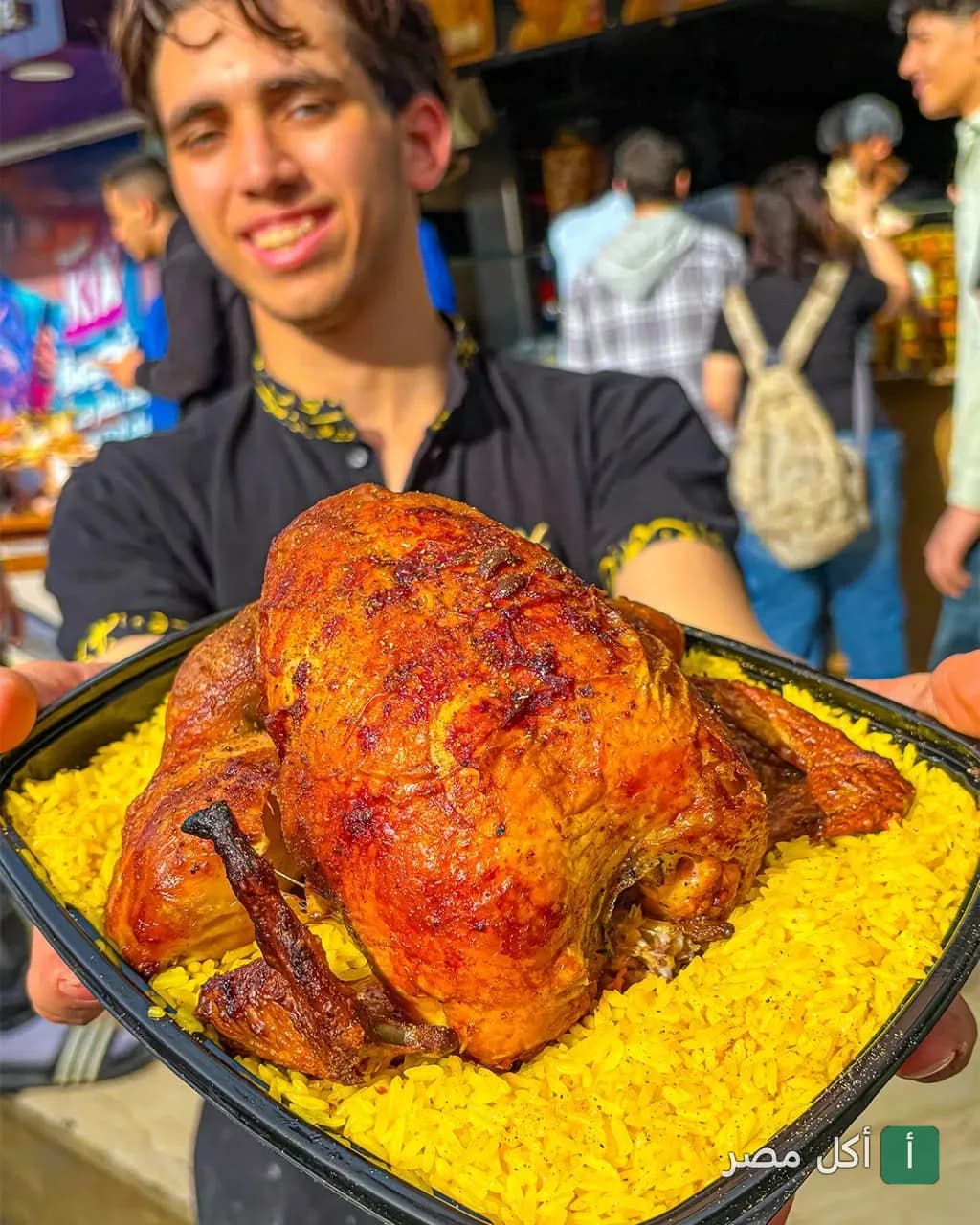 موظف في مطعم الدمشقي بطنطا يقدم وجبة دجاج مشوي مع أرز أصفر.