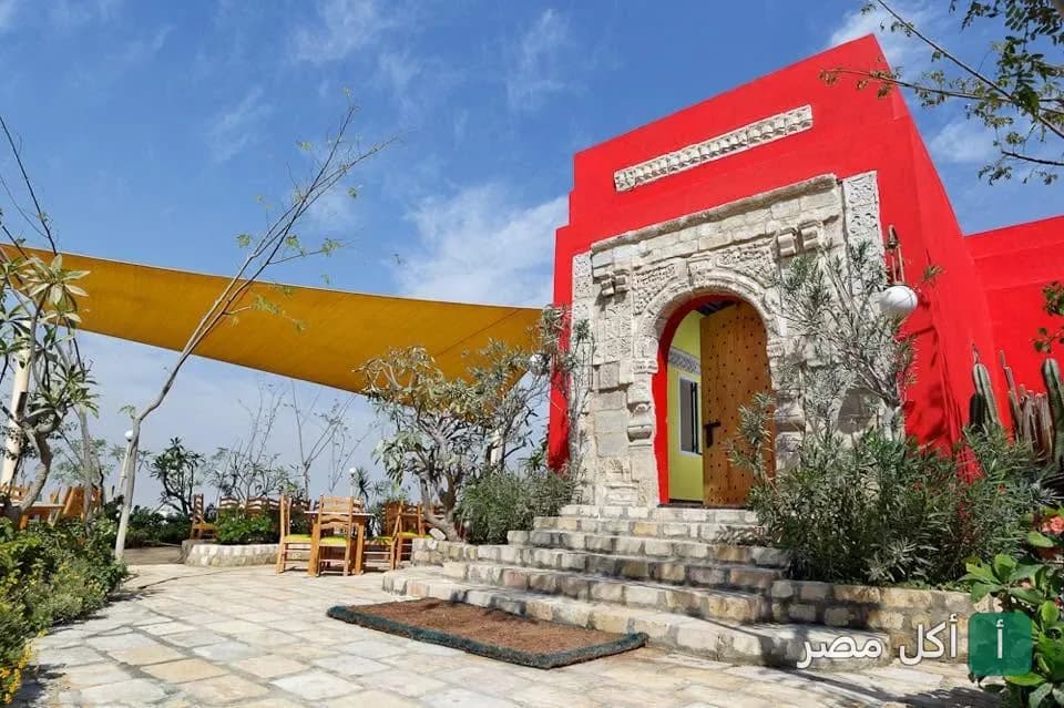 مدخل مطعم أندريا المريوطية بالجيزة، يتميز بواجهة حمراء زاهية وتصميم حجري تراثي مع جلسات خارجية مظللة.