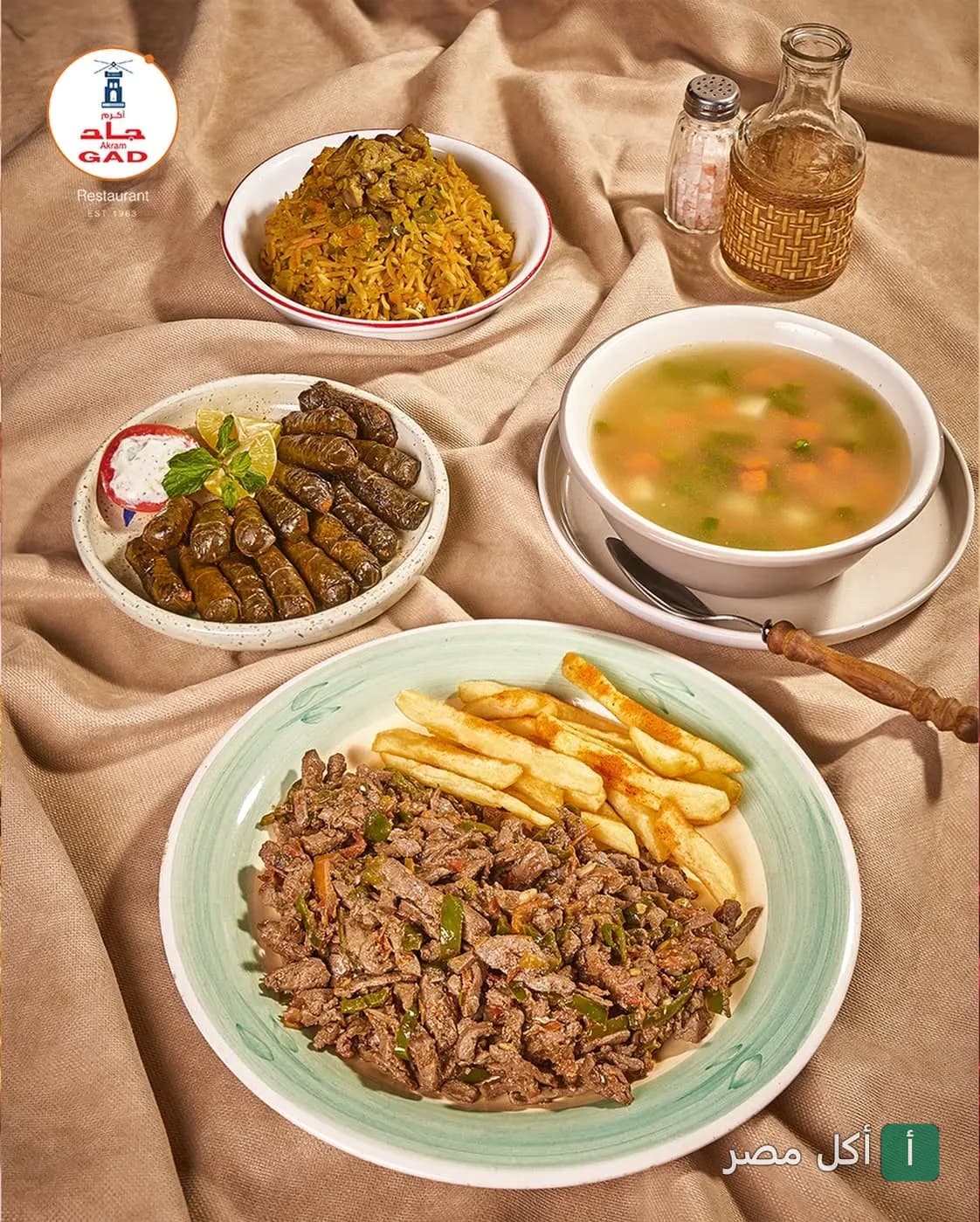 مائدة متنوعة من مطعم أكرم جاد بالجيزة تضم أطباق الأرز، ورق العنب، شوربة الخضار، وكبدة مع بطاطس محمرة.