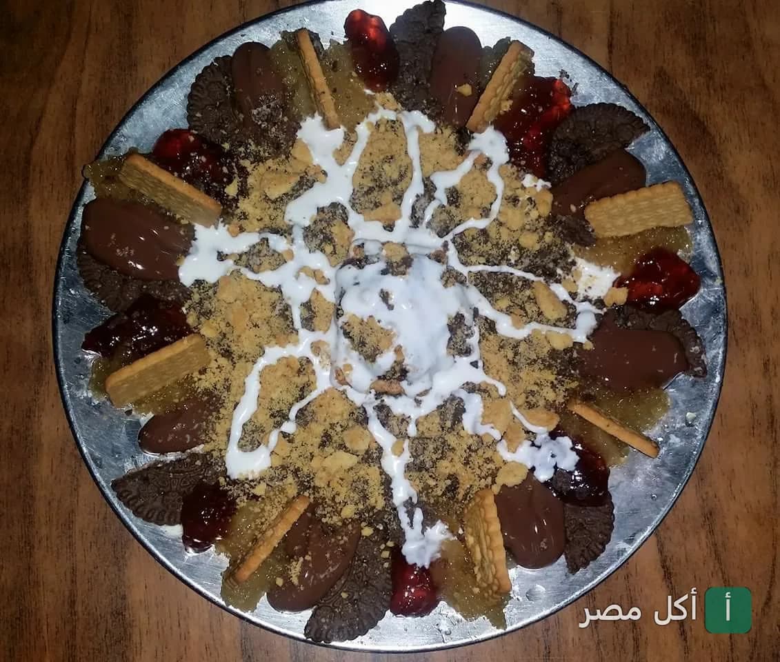 طبق حلويات متنوع من ألبان سويسرا بالإبراهيمية، الإسكندرية، مزين بالبسكويت والشوكولاتة وقطع الفواكه.