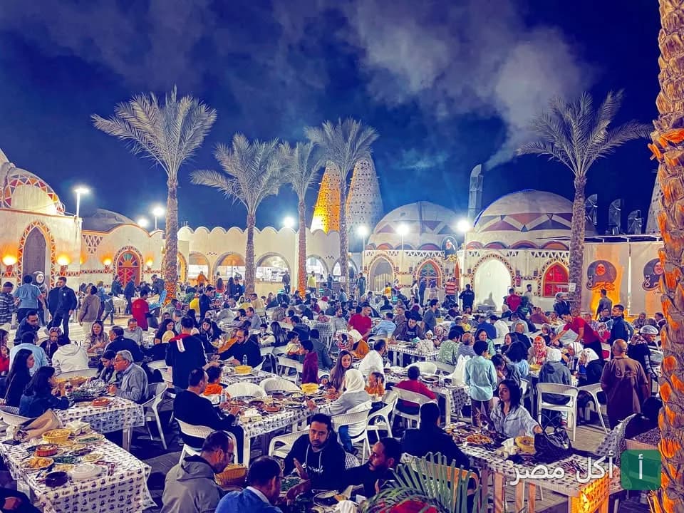 جلسات خارجية مزدحمة في مطعم حجوجة بالإسكندرية مع ديكورات شرقية وأشجار نخيل ليلاً.