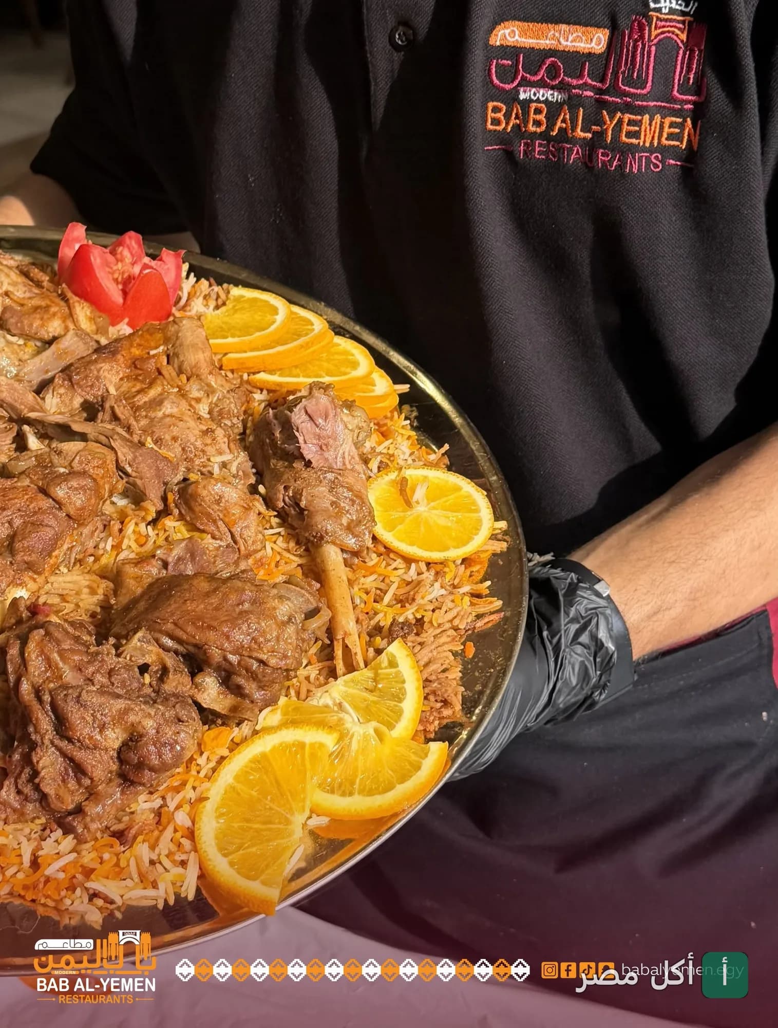 نادل يقدم طبق لحم ضاني مع أرز ومزين بشرائح البرتقال في مطاعم باب اليمن الحديث.