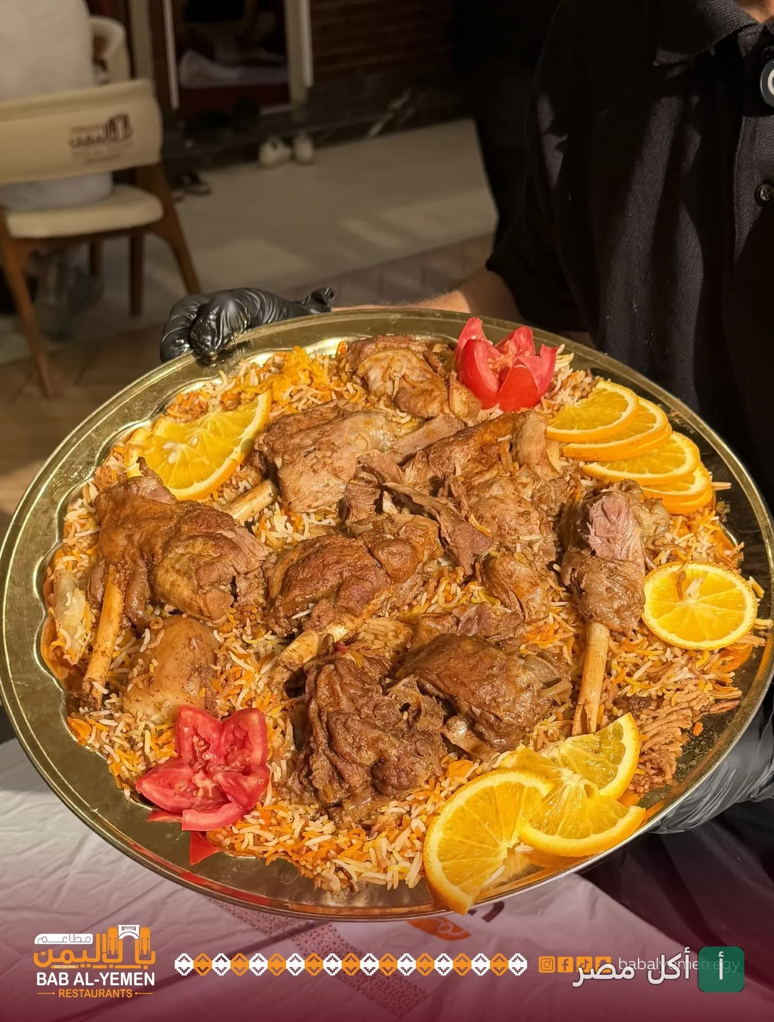 طبق كبير من الأرز باللحم المطهو على الطريقة اليمنية مزين بشرائح البرتقال والطماطم في مطاعم باب اليمن الحديث.