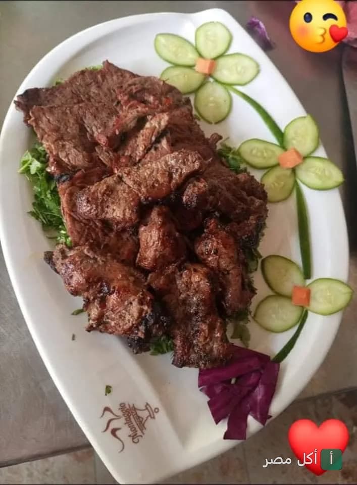 طبق مشويات مشكلة من مطعم القشيط في العلمين، يقدم مع شرائح الخيار المقطعة على شكل زهور.