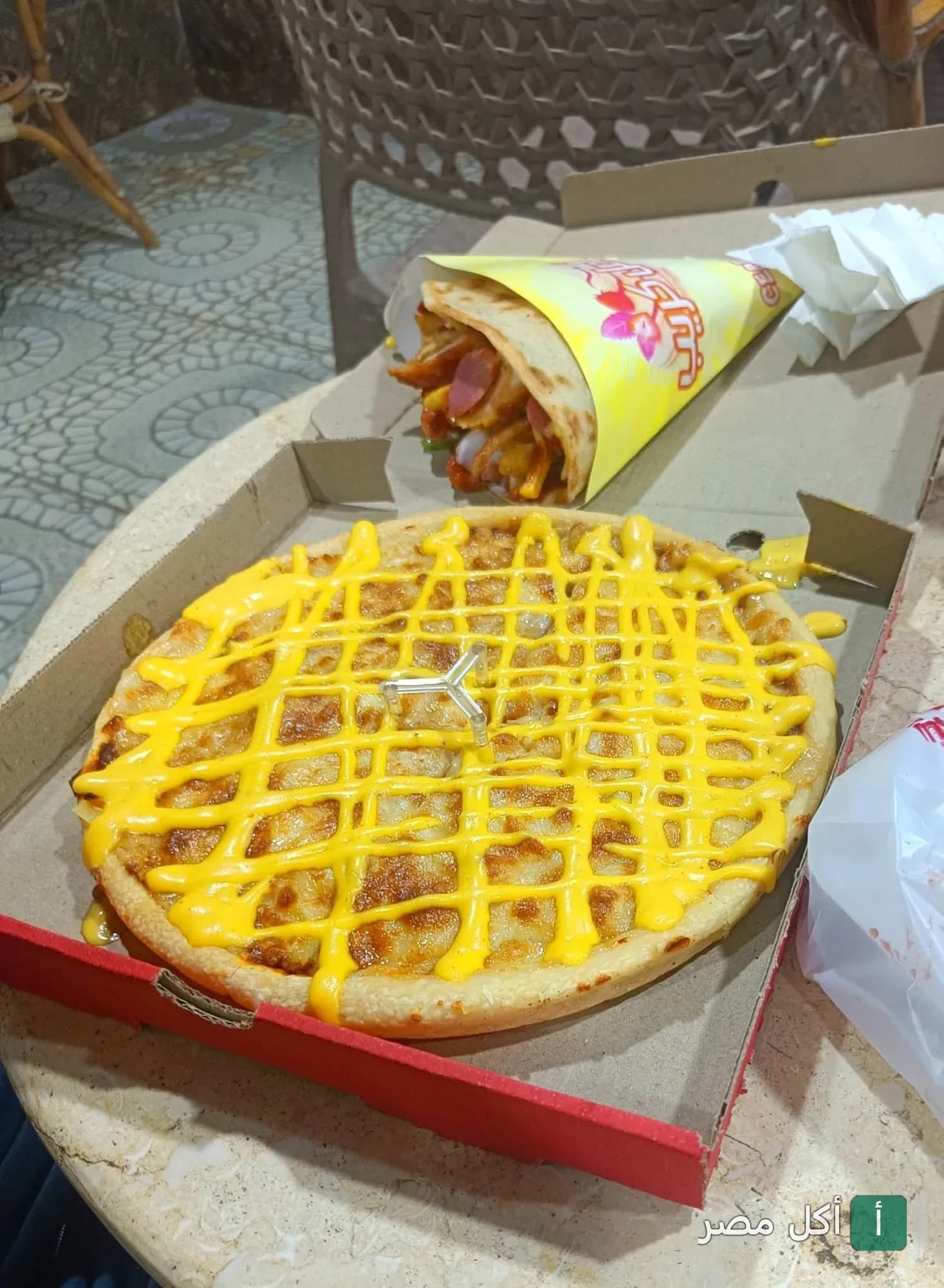 بيتزا مغطاة بصوص الجبن الأصفر بجانب ساندوتش كريب في مطعم زادي بيتزا بالسنطة.