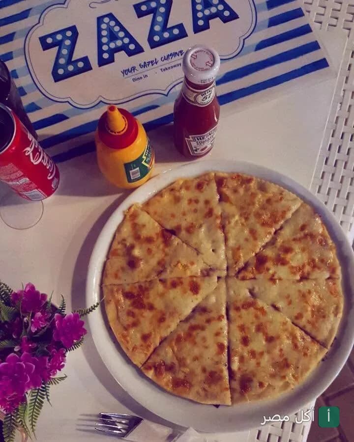 بيتزا بالجبنة مقطعة على طاولة في مطعم ظاظا كوزين بالزمالك مع كاتشب ومستردة.