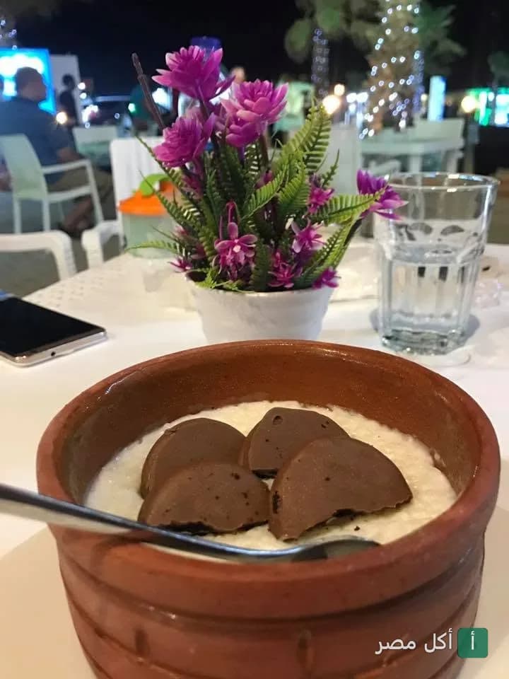 طاجن حلوى في مطعم ظاظا كوزين بالزمالك مع زينة ورد على الطاولة.