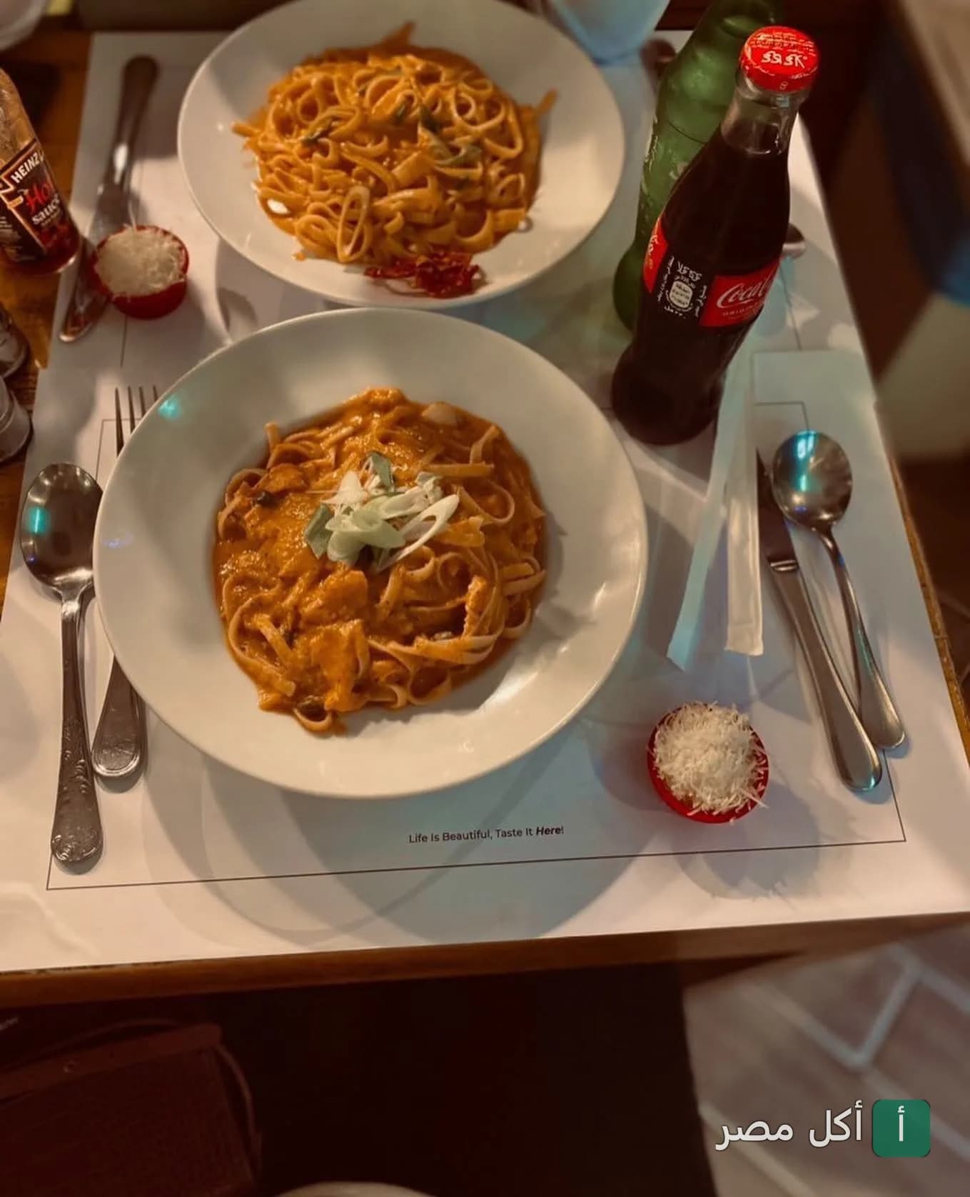 أطباق مكرونة بصوص أحمر في مطعم أوس باستا بالزمالك مع مشروب غازي وجبن مبشور.