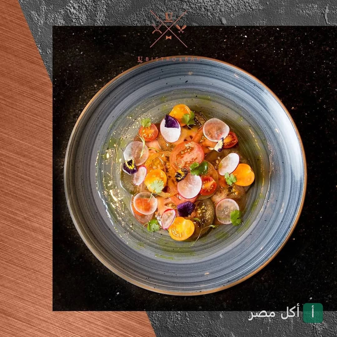 طبق سلطة طماطم ملونة مزينة بالخضروات والزهور في مطعم يو بيسترو وبار بالزمالك.