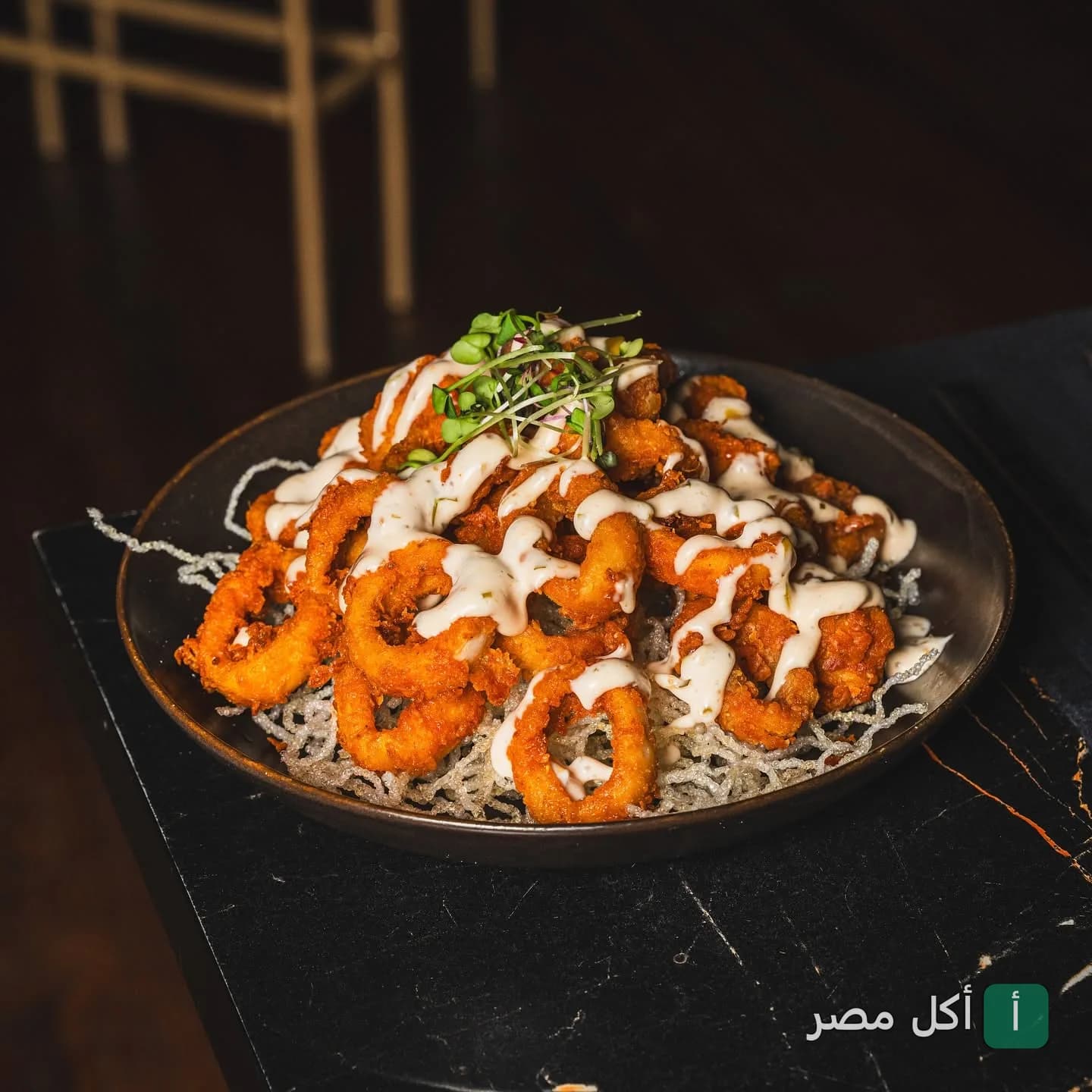 طبق كاليماري مقلي مغطى بصوص كريمي في مطعم كازان بالزمالك.
