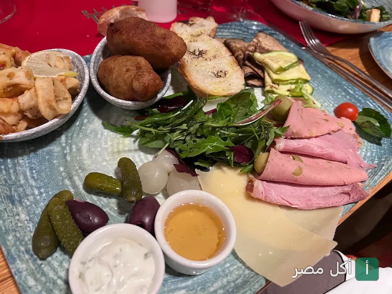 طبق مقبلات متنوع يضم اللحوم الباردة، الجبن، الزيتون، والمخللات في مطعم توسكاني بالزمالك.