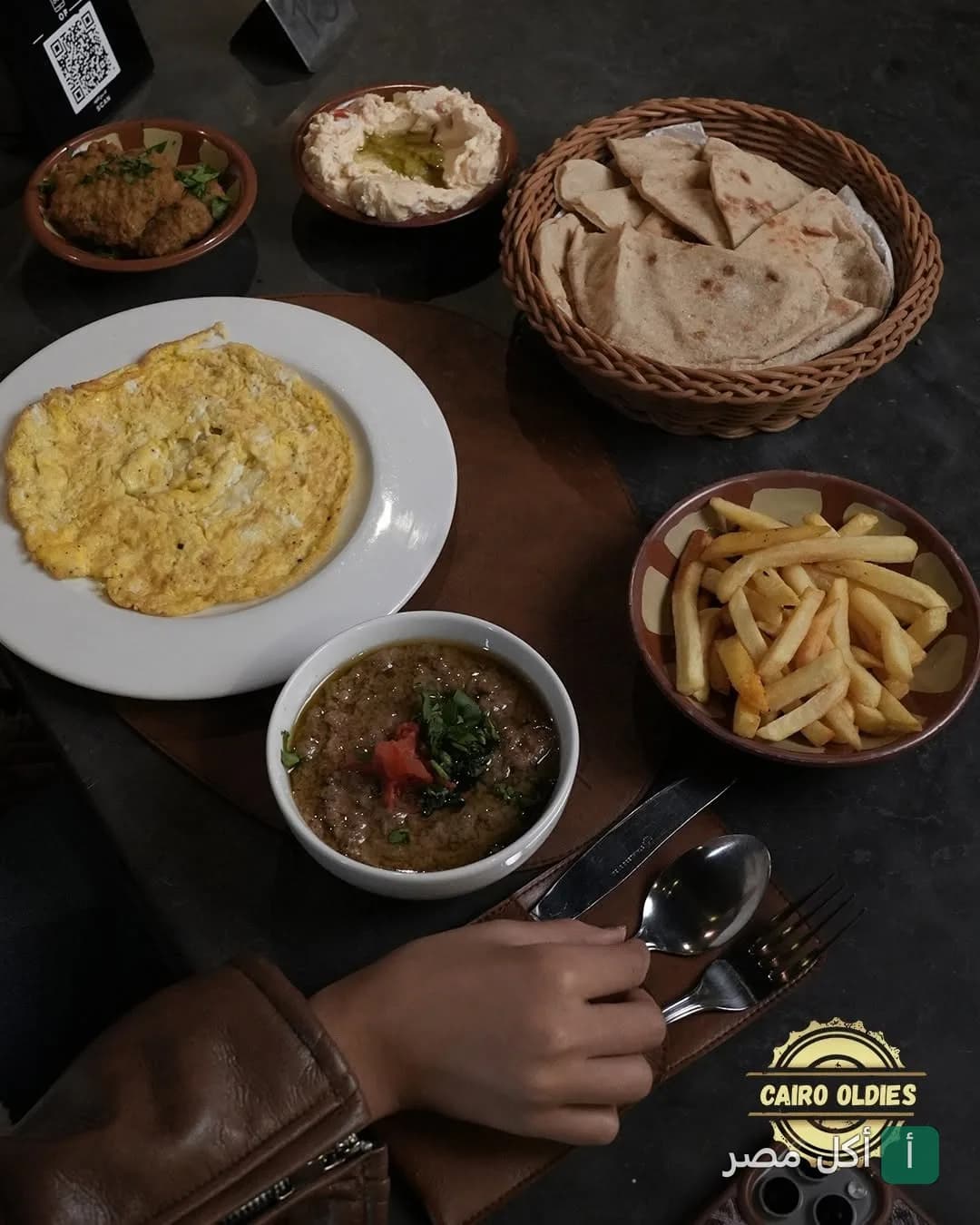 سفرة فطور متنوعة تضم أومليت، فول، حمص، بطاطس مقلية وخبز بلدي في مطعم كايرو أولديز بالمنيل.