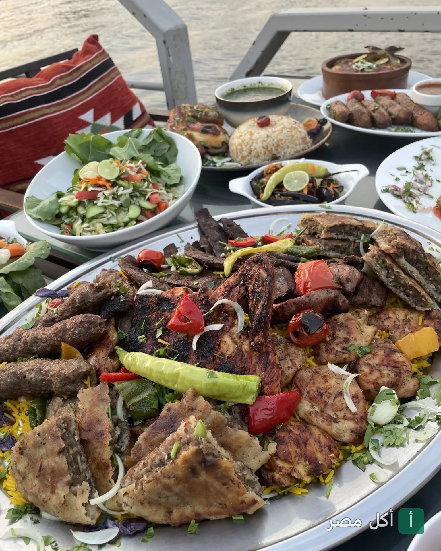 مائدة طعام متنوعة تضم مشاوي مصرية وأطباق جانبية في مطعم بنت السلطان المطل على النيل بالقاهرة.