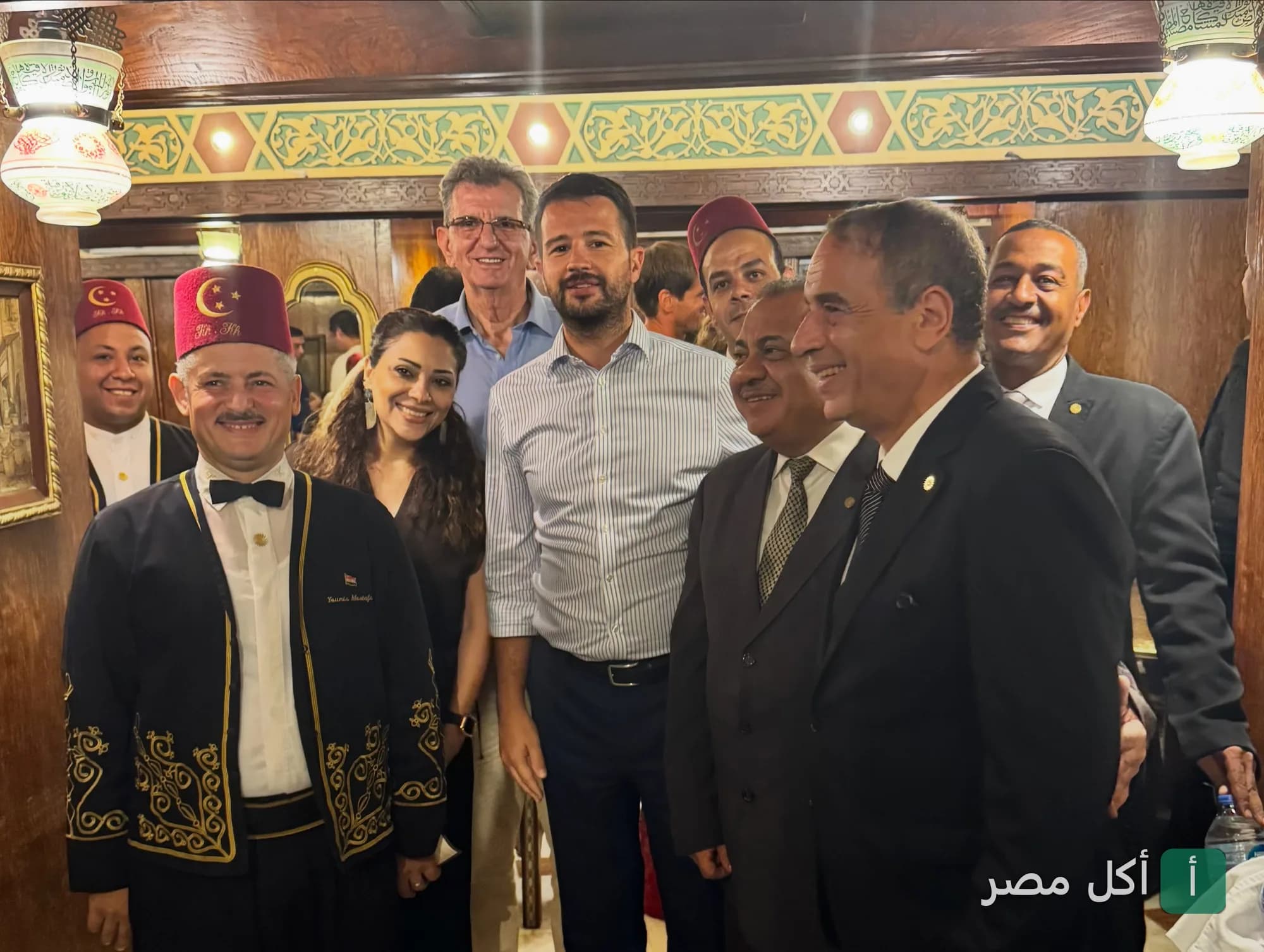 مجموعة من الأشخاص يبتسمون داخل مقهى نجيب محفوظ في خان الخليلي بالقاهرة.