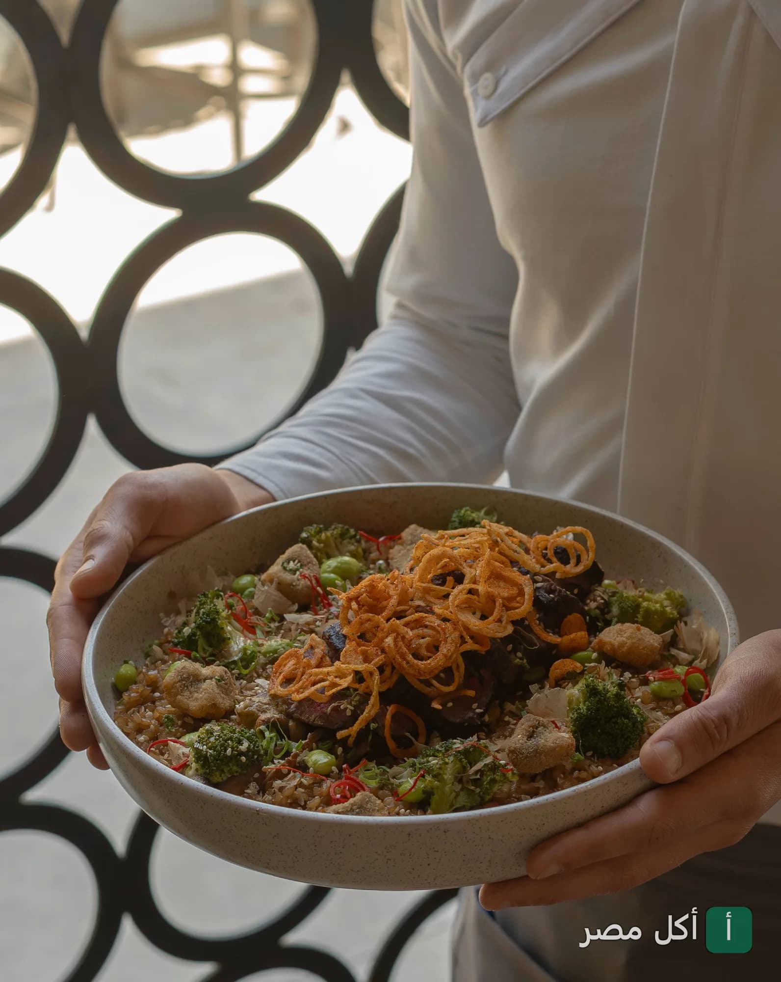 نادل يقدم طبق أرز مع خضروات وبروكلي وبصل مقرمش في مطعم كازوكو بالتجمع الأول.