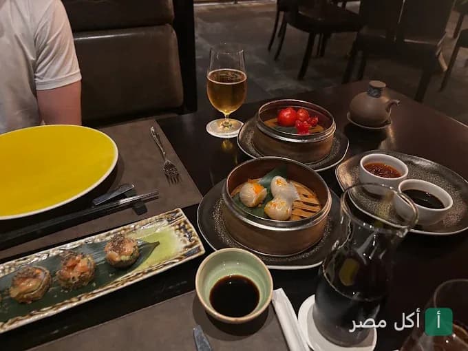 مائدة طعام متنوعة في مطعم تيانما ببولاق القاهرة، تضم أطباق ديم سام في أواني بخارية وصوصات.