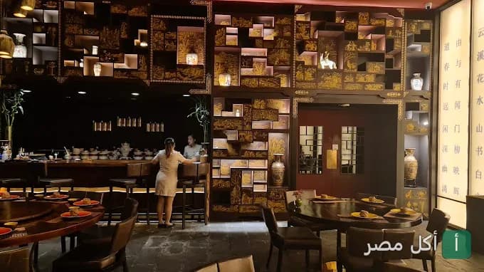 ديكور داخلي مستوحى من الطراز الآسيوي في مطعم تيانما بالقاهرة، يظهر بار وموائد طعام خشبية مزخرفة.