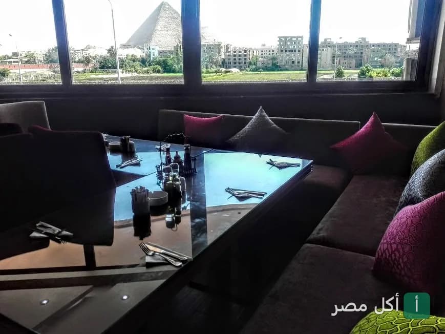 طاولات طعام داخل مطعم ذا فيو في القاهرة مع إطلالة مباشرة على الأهرامات.