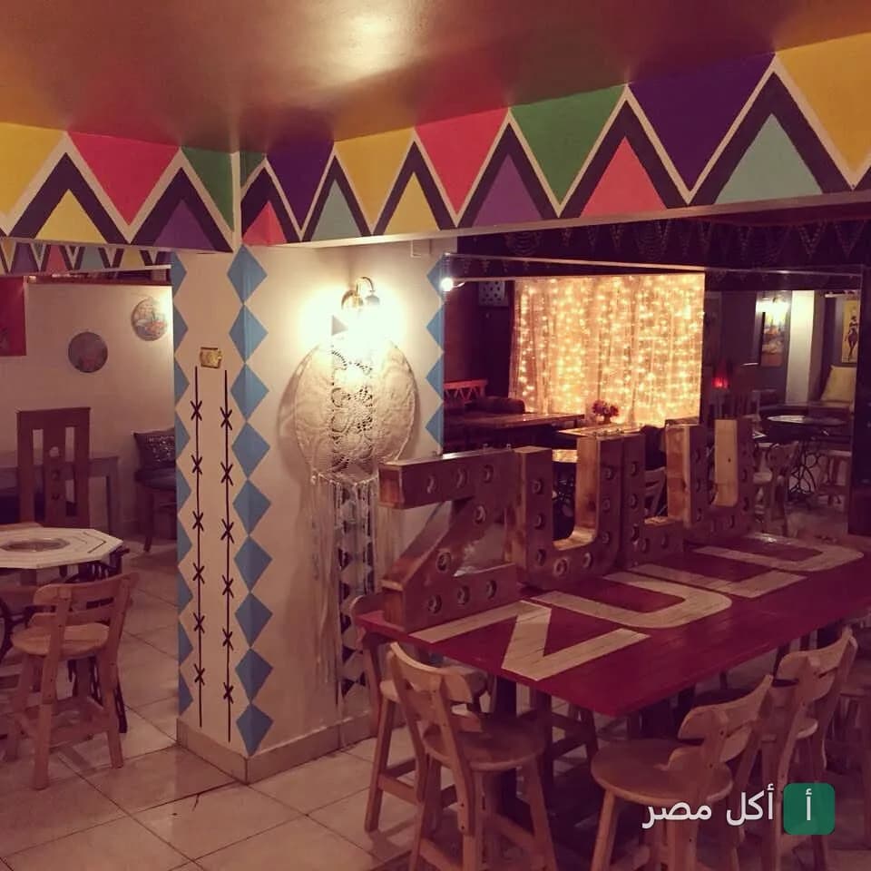ديكور داخلي ملون في مطعم زولو بالمعادي، يظهر طاولة خشبية عليها حروف اسم المطعم وإضاءة دافئة.