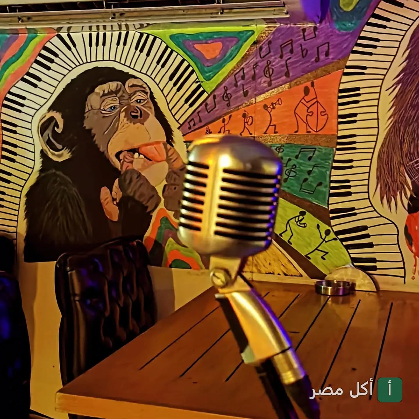ميكروفون كلاسيكي أمام حائط مزين برسومات فنية ملونة في مطعم زولو بالمعادي.