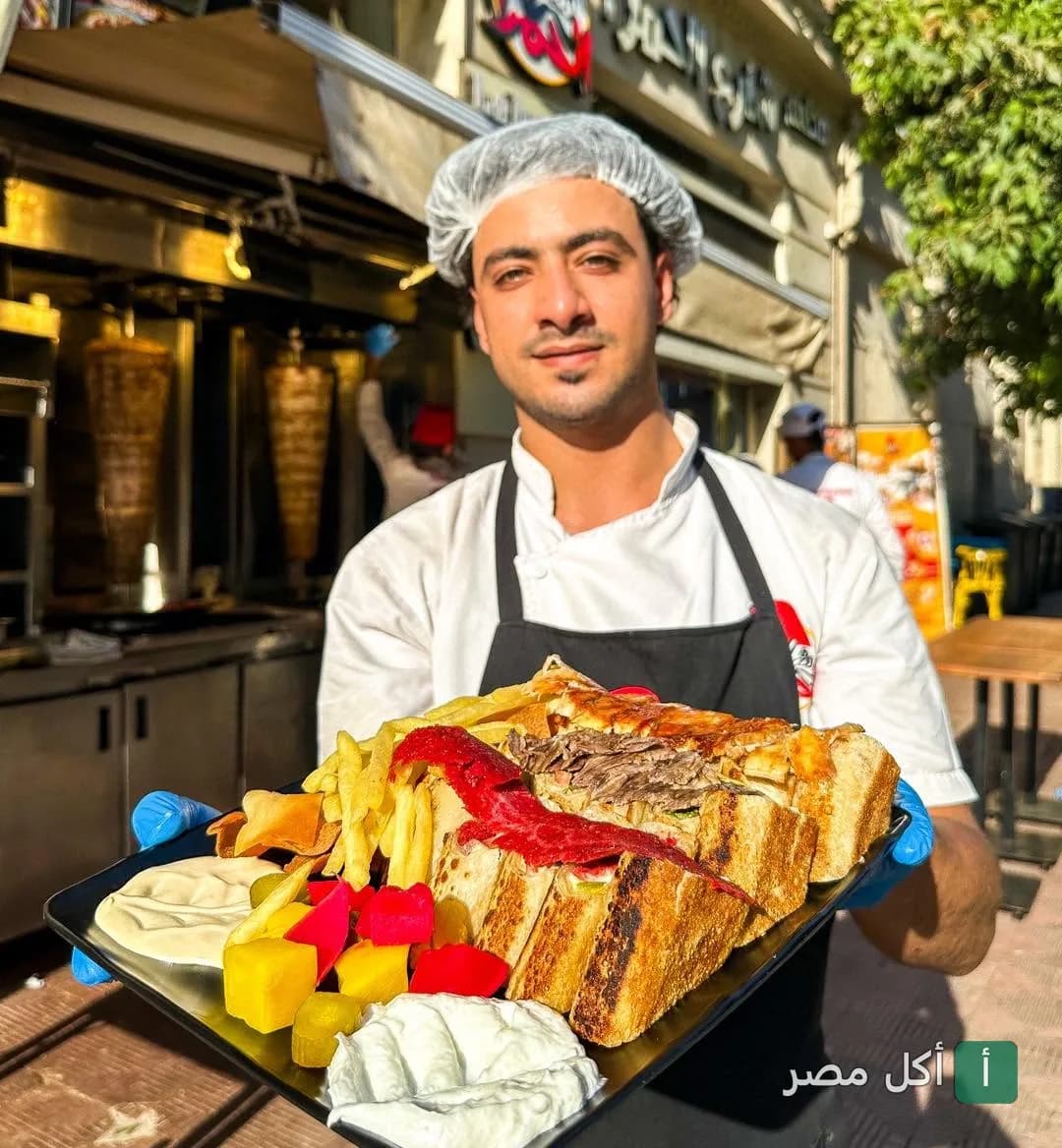 شيف مطعم شارع الحمرا بباب اللوق يقدم طبق شاورما مع بطاطس ومخللات.