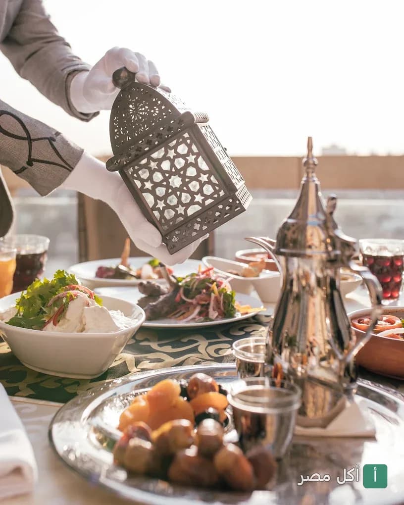 نادل يرتدي قفازات يضع فانوس رمضان على مائدة إفطار شرقية في مطعم سيروكو بالقاهرة.