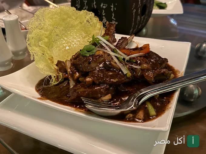 طبق ريش لحم بصوص داكن ومزين برقاقة مقرمشة في مطعم ٨ بقصر النيل