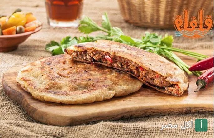 رغيف حواوشي مصري ساخن ومحشو باللحم المفروم على لوح تقطيع خشبي في مطعم فلفلة إكسبريس بالقاهرة.