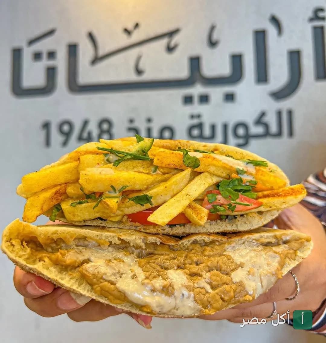 ساندوتش فول بالبطاطس في مطعم أرابياتا، يظهر شعار المطعم في الخلفية.