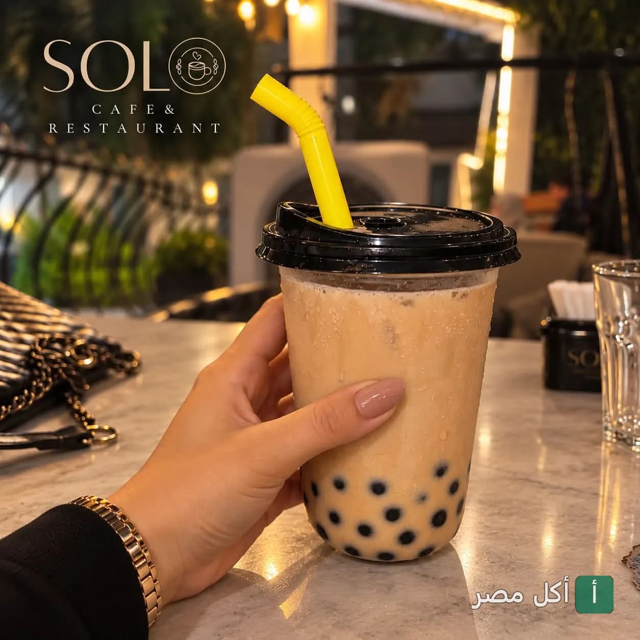 يد تمسك كوب شاي بابلز (بوبا) في مطعم وكافيه سولو بميدان عمان في الدقي.