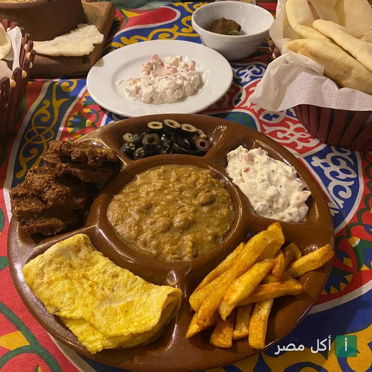 طبق فطور مصري متنوع يحتوي على فول وطعمية وبيض مقلي وبطاطس محمرة في مطعم سيف هاوس بالدقي.